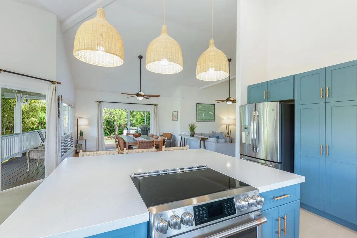 Una luminosa cocina abierta al comedor, con gabinetes azules y una isla amplia.