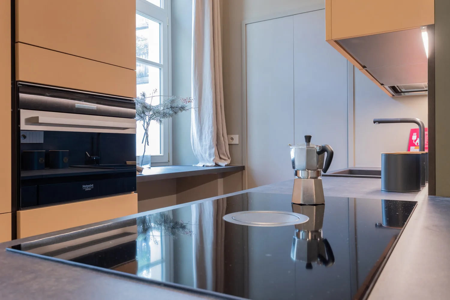 A modern kitchen with a black cooktop, built-in oven, and countertop.