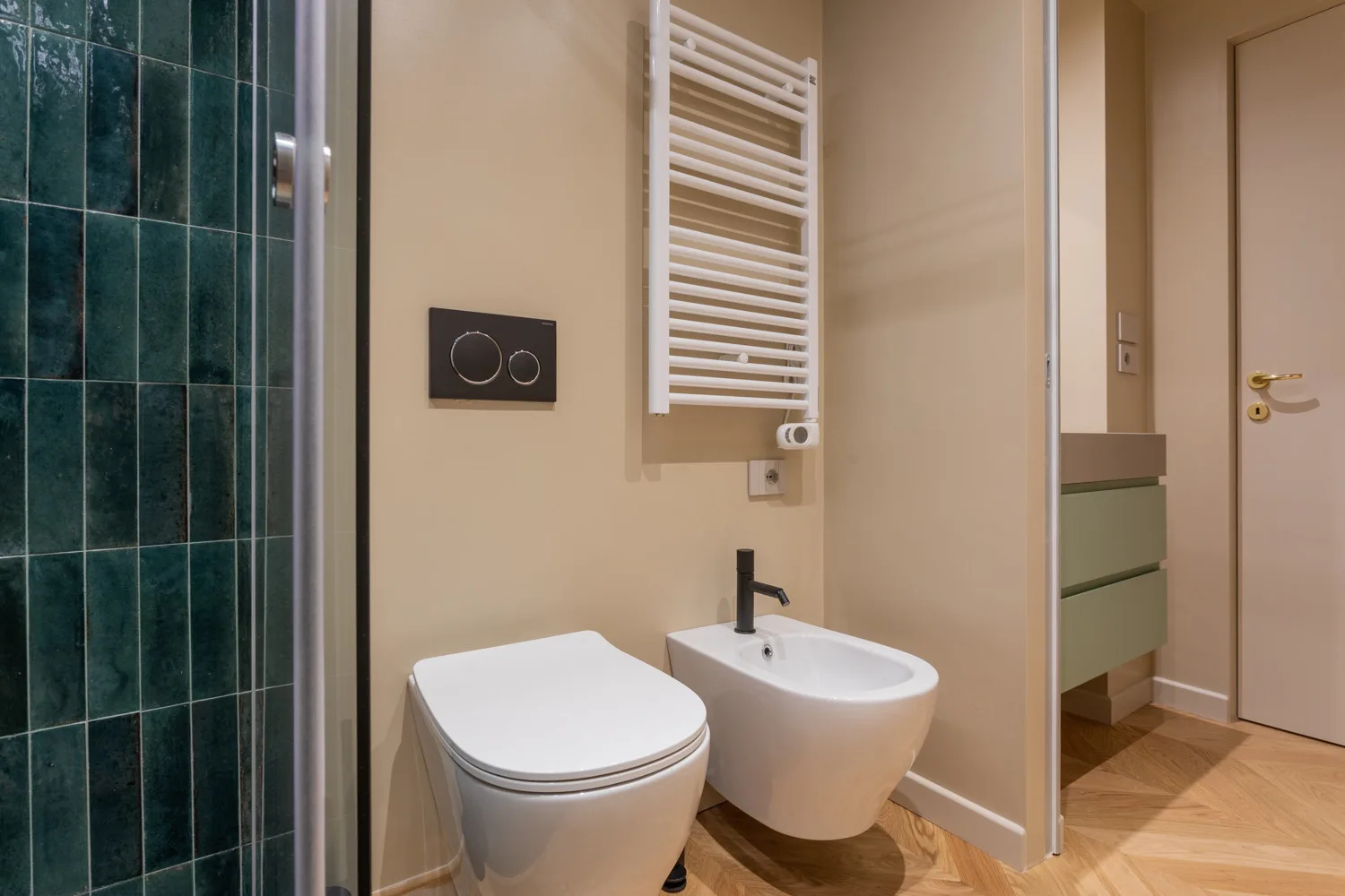A bathroom with a toilet, wall-mounted sink, and towel warmer.