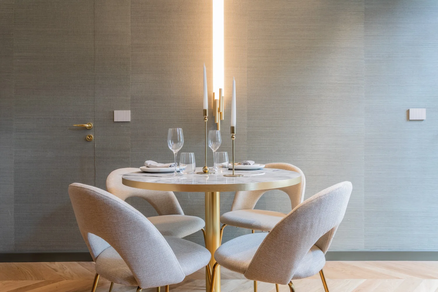 A dining area with a round table, set with plates and glasses.