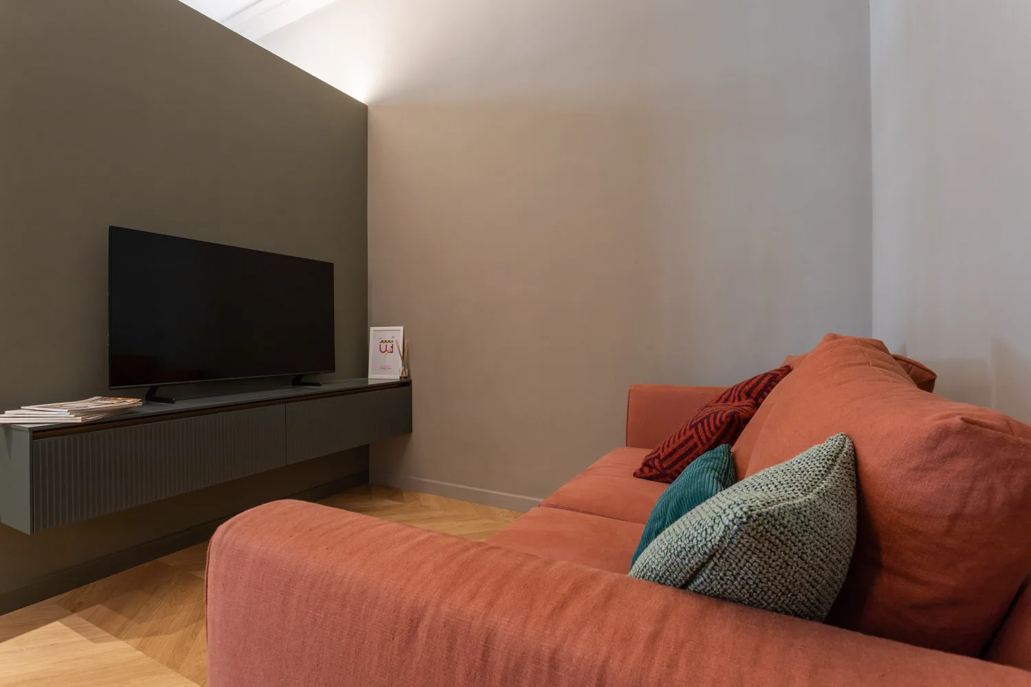 A living room with a television on a low console and a sofa.