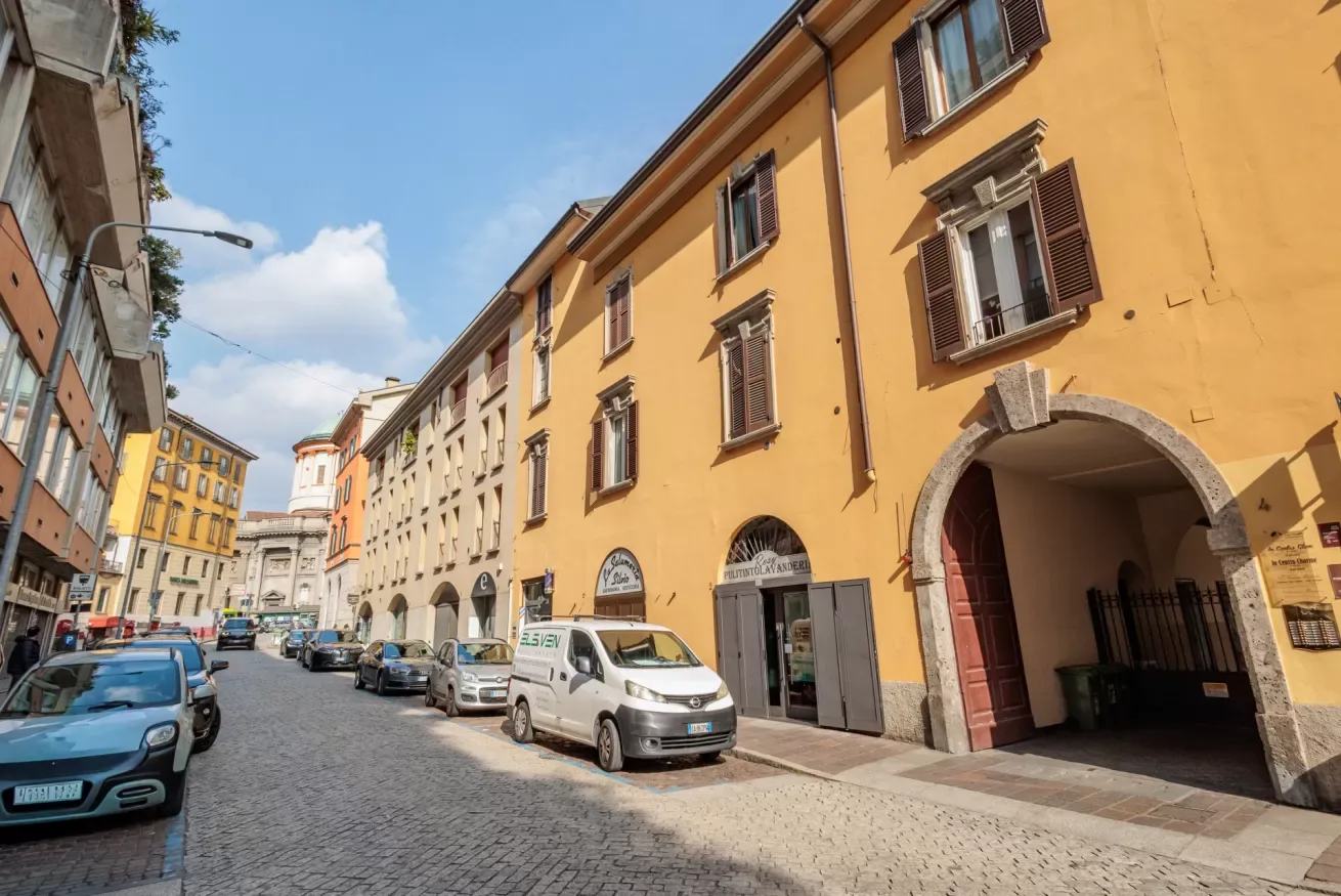 Una calle empedrada bordeada de edificios coloridos y coches estacionados.