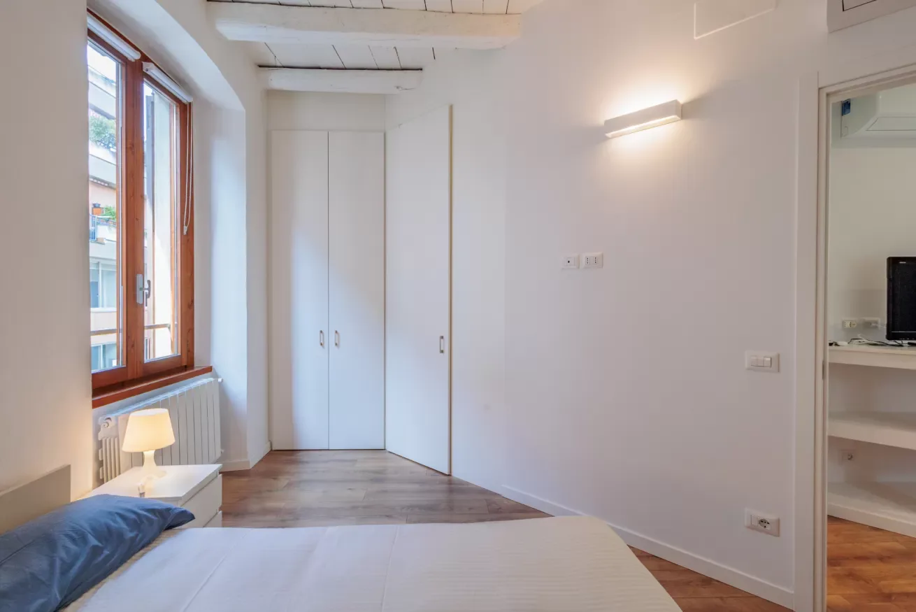 Un dormitorio luminoso con una cama, un armario y una ventana grande.