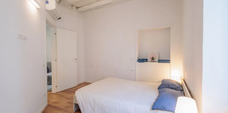 Un dormitorio luminoso con una cama y un nicho en la pared.