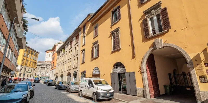 Una calle soleada bordeada de edificios coloridos y coches aparcados.
