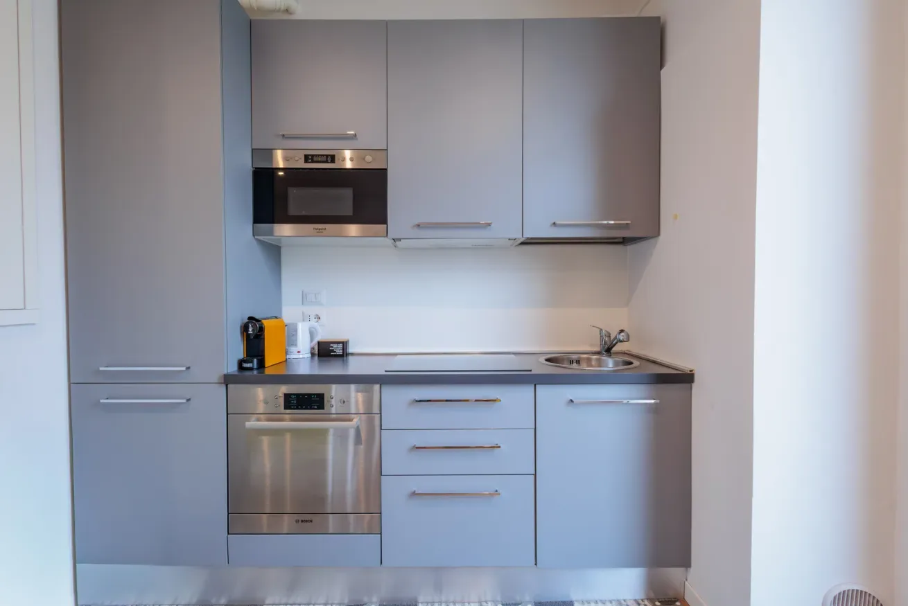 Una cocina compacta con gabinetes grises, una placa de cocina y electrodomésticos integrados.