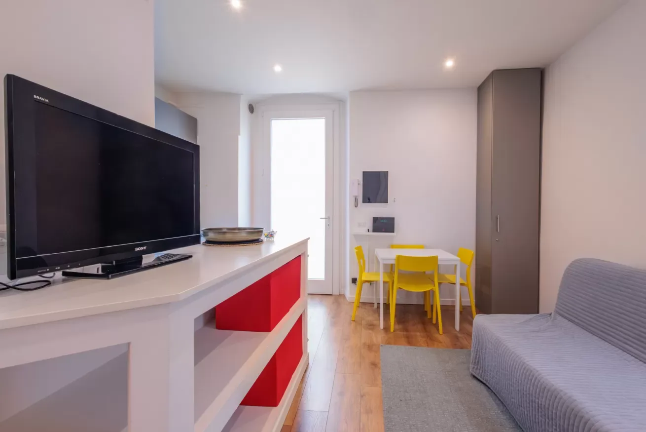 Una luminosa sala de estar con televisor, mesa de comedor y asientos.