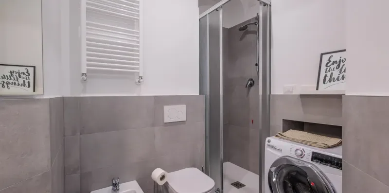 Un baño moderno con ducha, inodoro y lavadora.