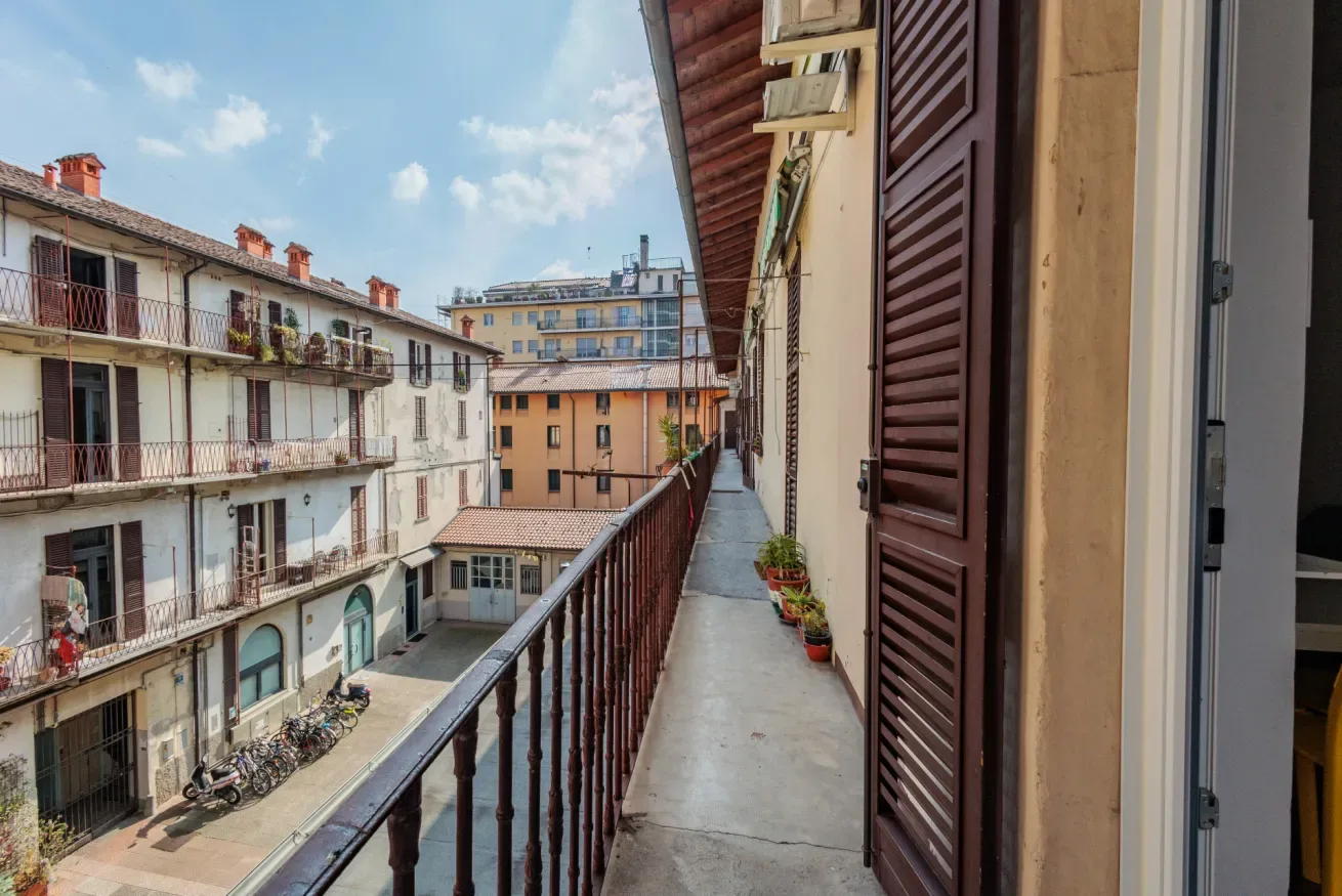Un estrecho pasillo exterior de balcón da a edificios de apartamentos vecinos.