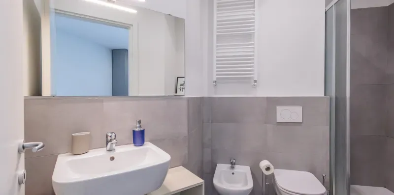 Un baño con lavabo, inodoro, bidé y radiador toallero montado en la pared.