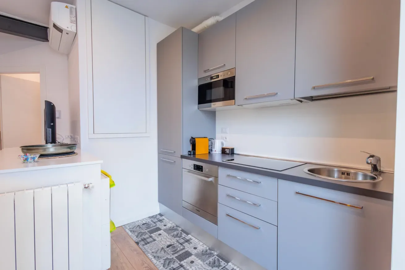 Una cocina compacta con gabinetes grises, una encimera y un fregadero.