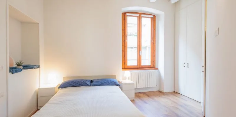 Un dormitorio con una cama, una ventana y armarios empotrados.