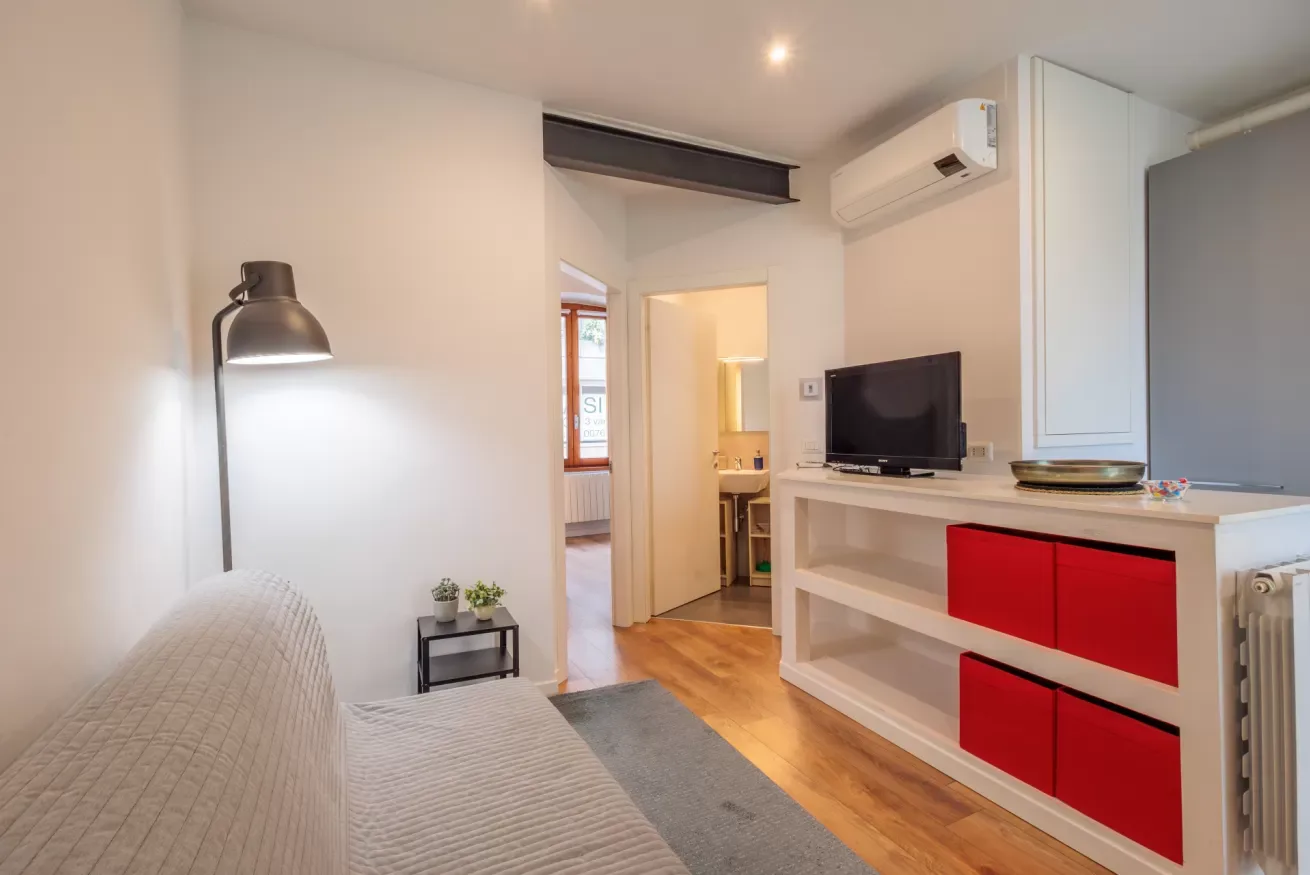 Una sala luminosa con asientos, un televisor y armarios rojos.