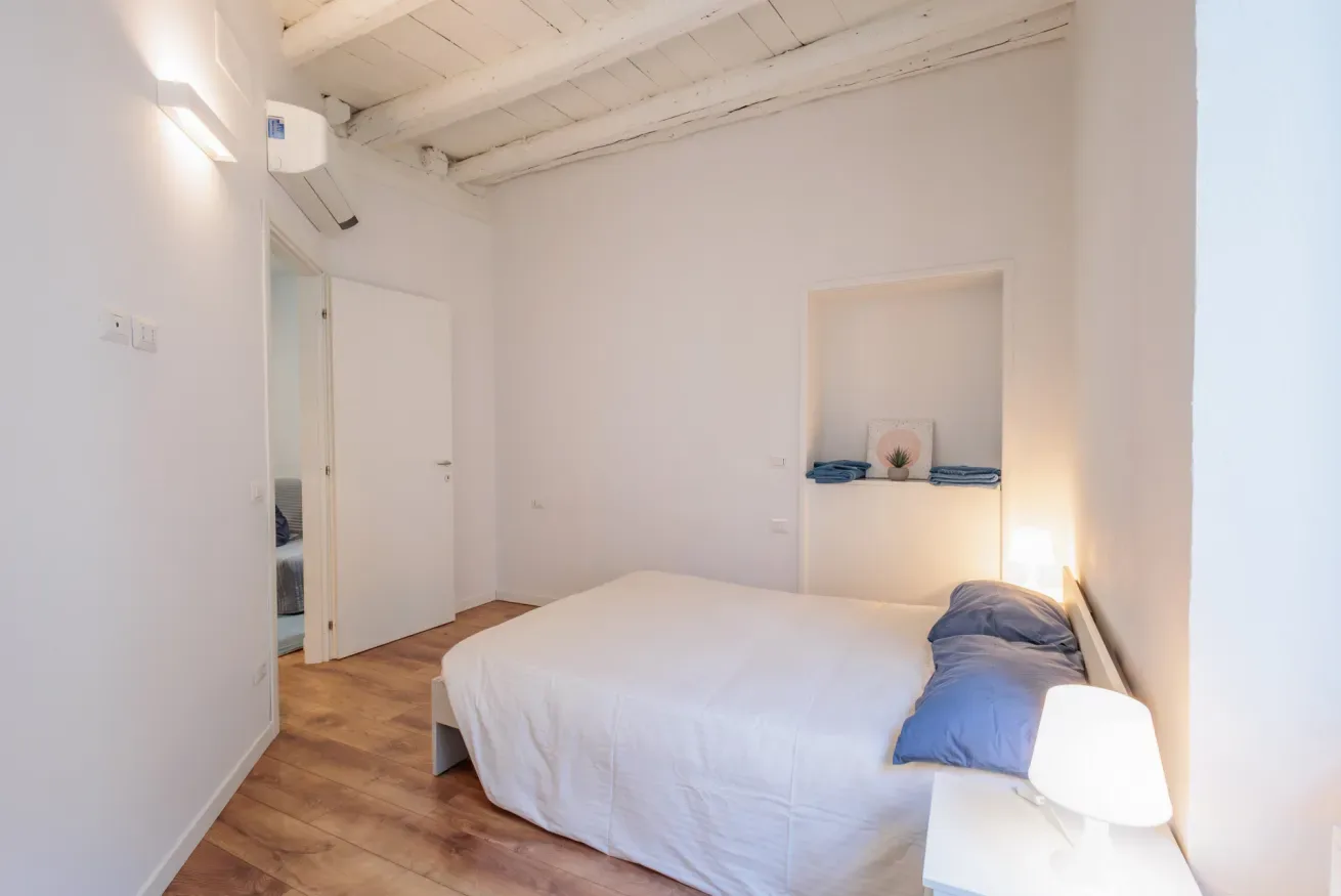 Dormitorio con una cama, una lámpara de noche y un estante empotrado.