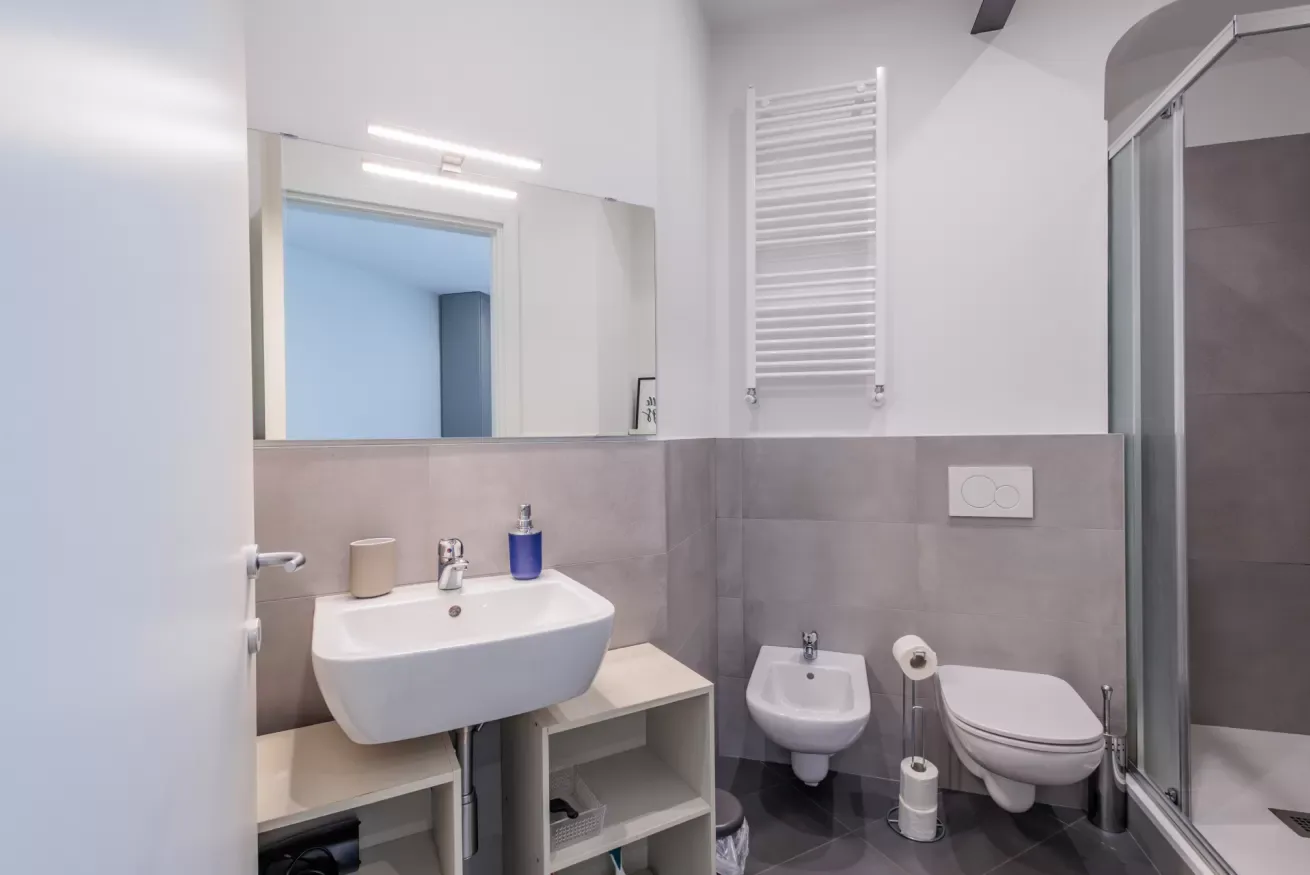 Un baño moderno con lavabo, inodoro suspendido y ducha de cristal.