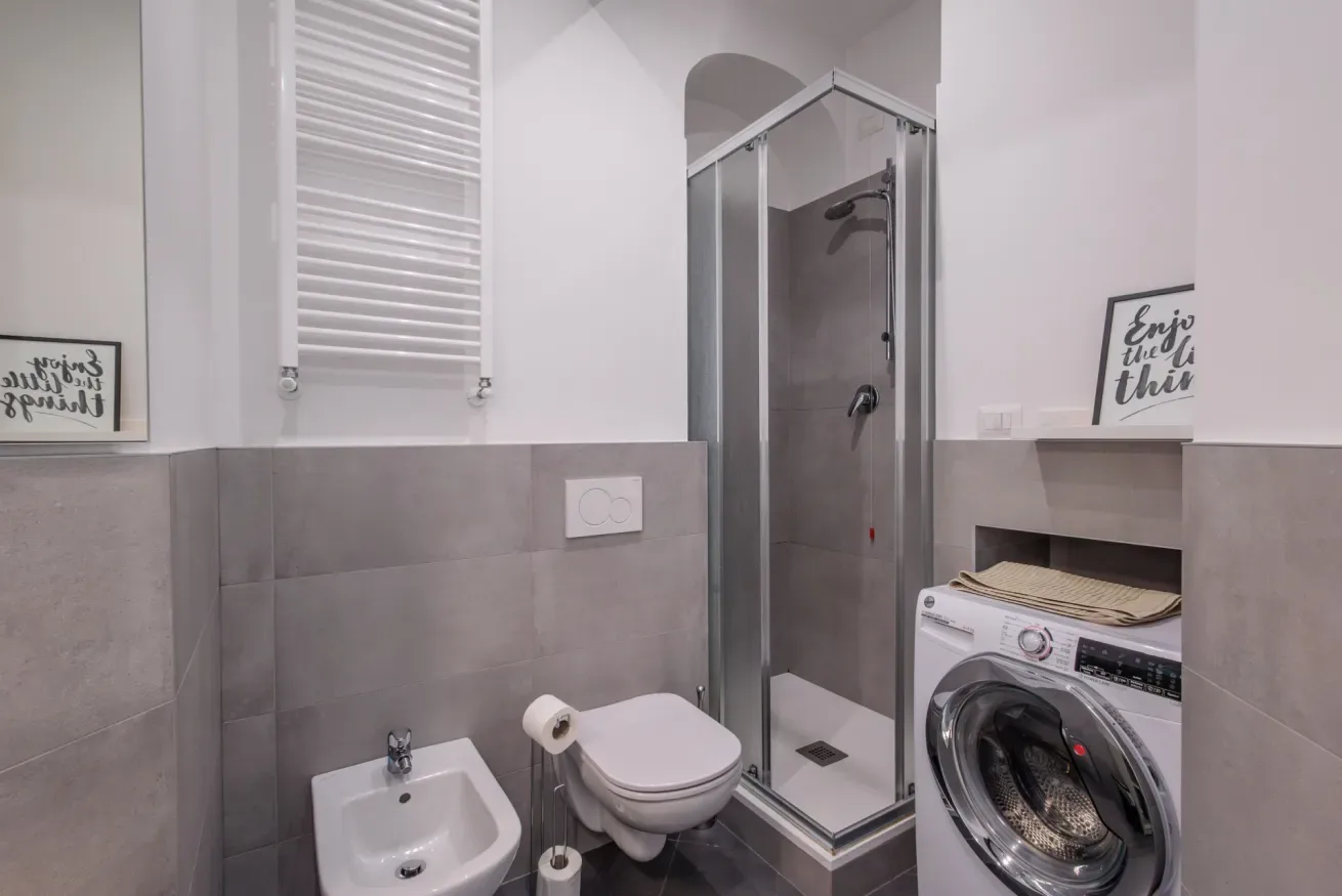 Un baño con ducha, inodoro, lavabo y lavadora.
