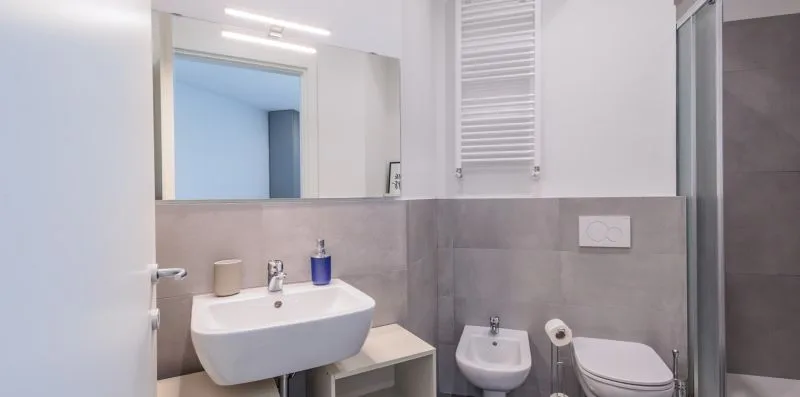 Un baño con lavabo, inodoro y bidé junto a una ducha de vidrio.