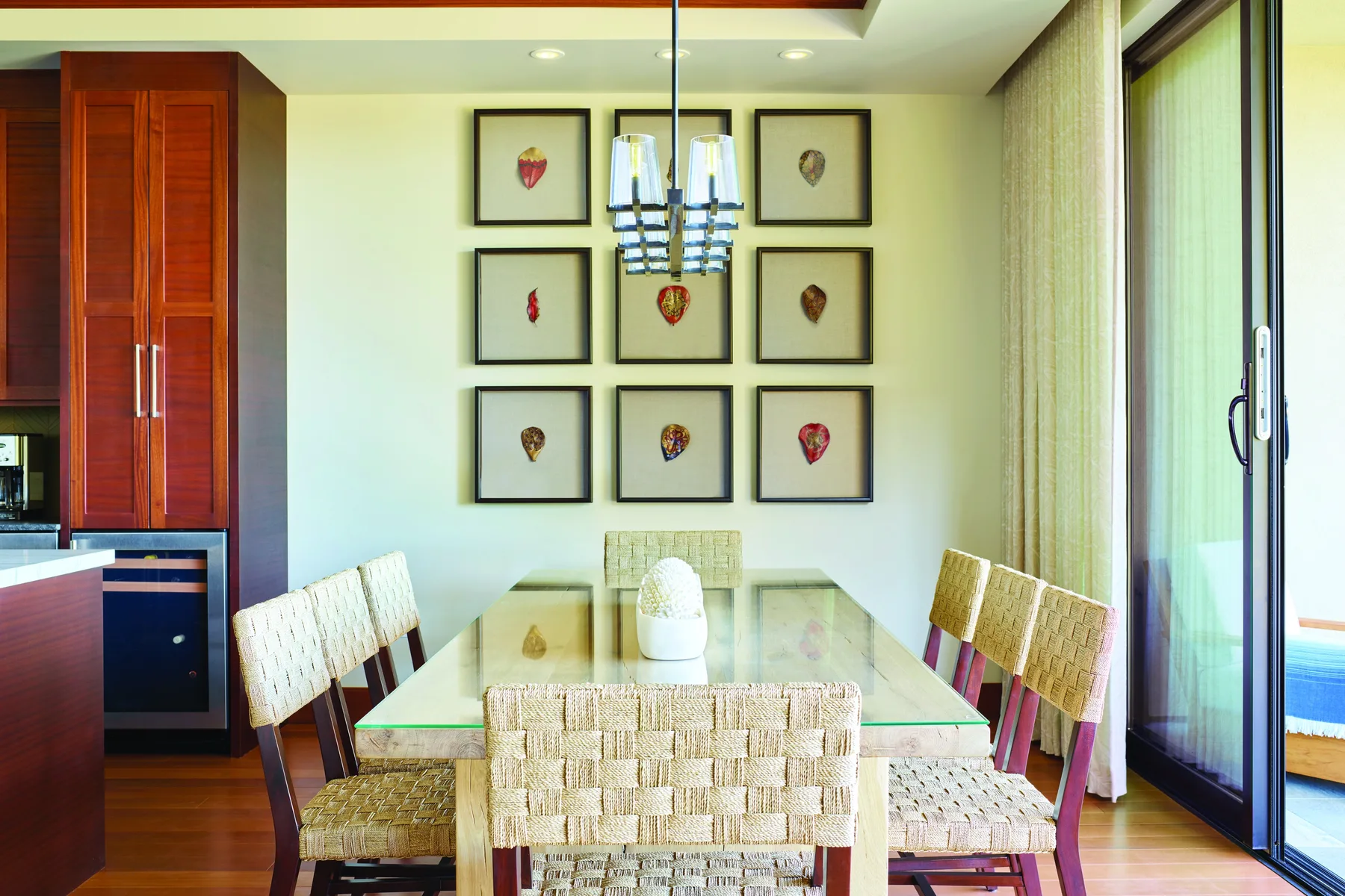 Un comedor con una mesa de vidrio y cuadros enmarcados en la pared.