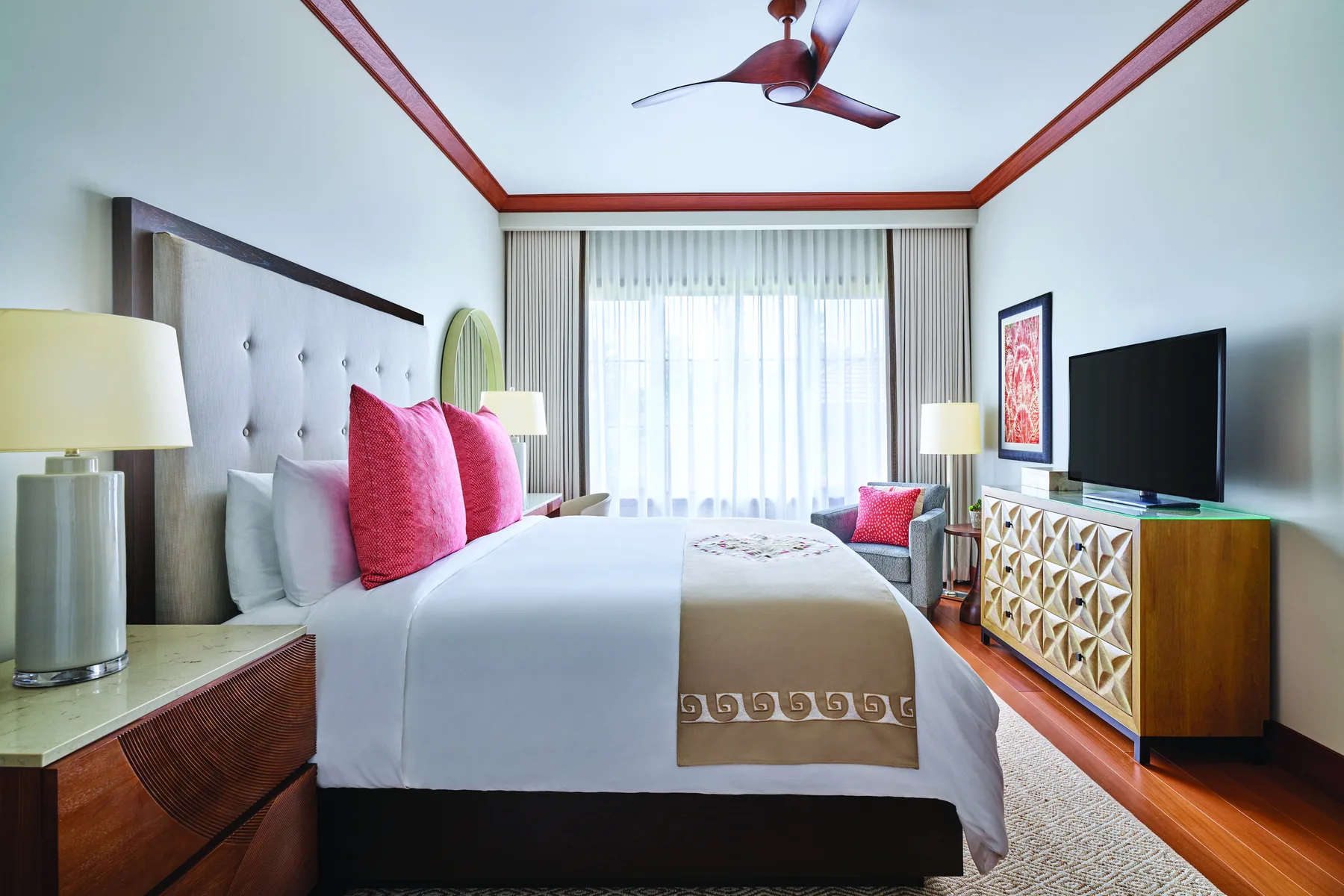 Un dormitorio con una cama tendida, cortinas luminosas y un televisor.