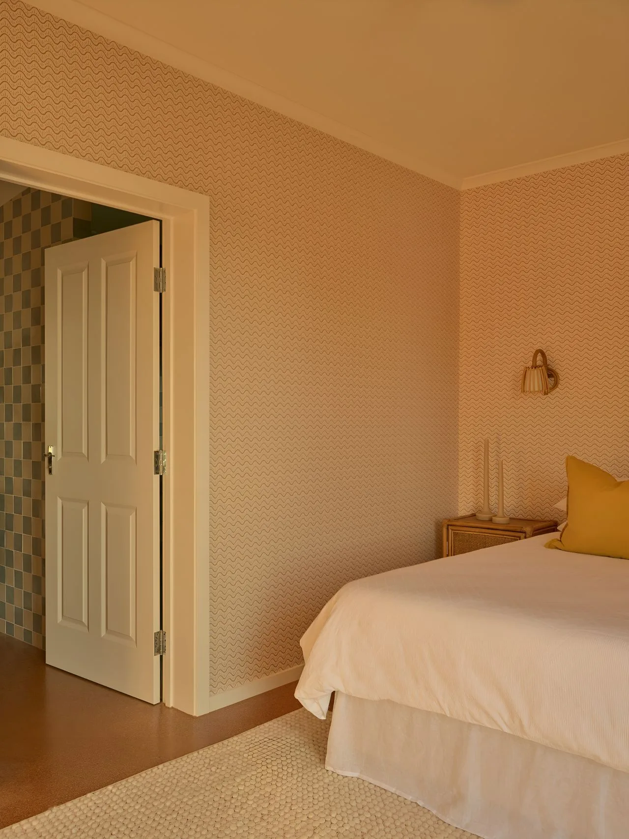 A bedroom with a neatly made bed and an open doorway.