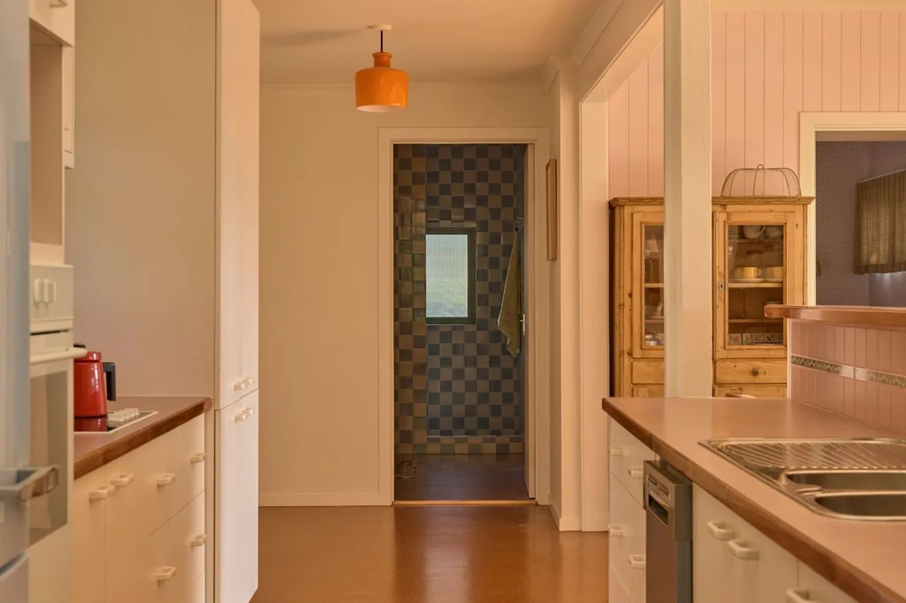 A kitchen with counters and cabinets opens onto a hallway.