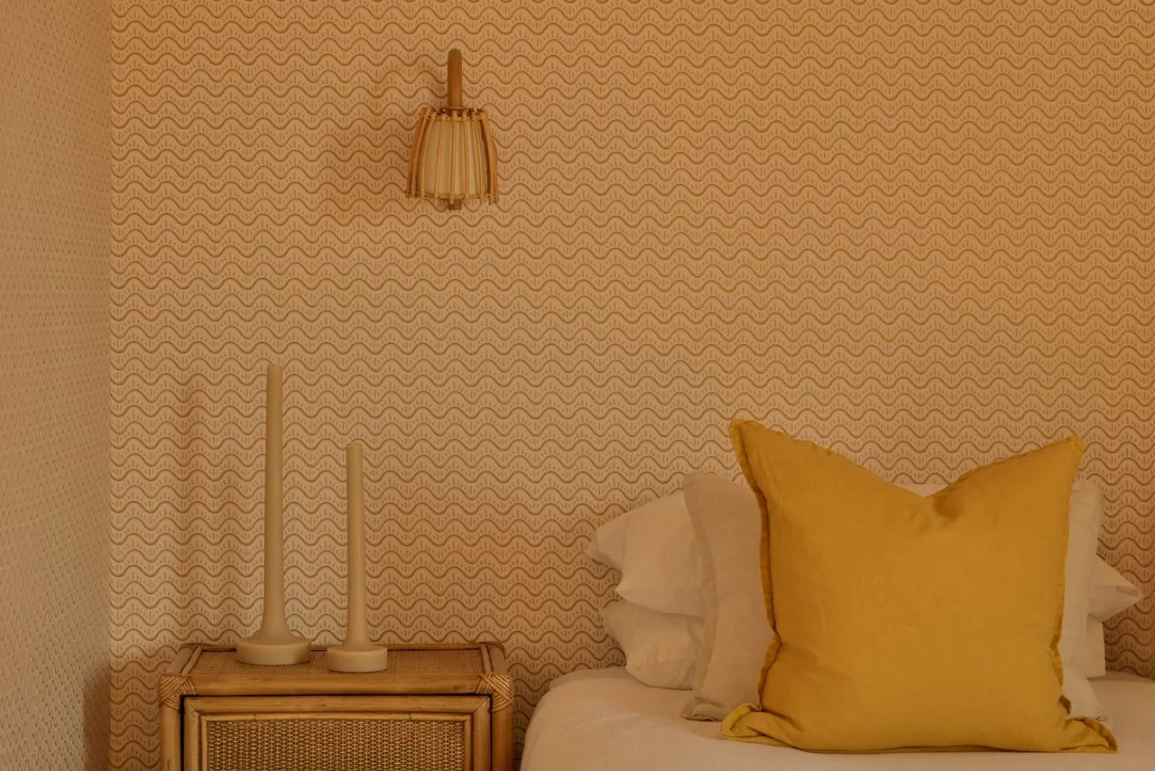 A bedroom with a bed, yellow accent pillow, and bedside table.