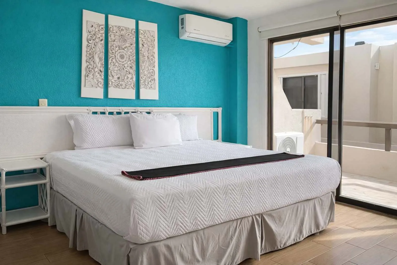 A bedroom with a large bed and sliding glass doors opening onto a balcony.