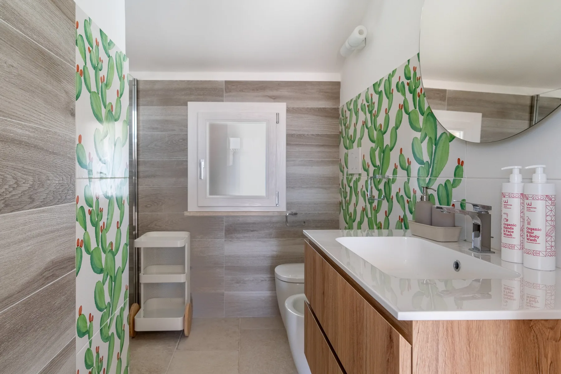A bathroom with a sink vanity and cactus-patterned wall tiles.
