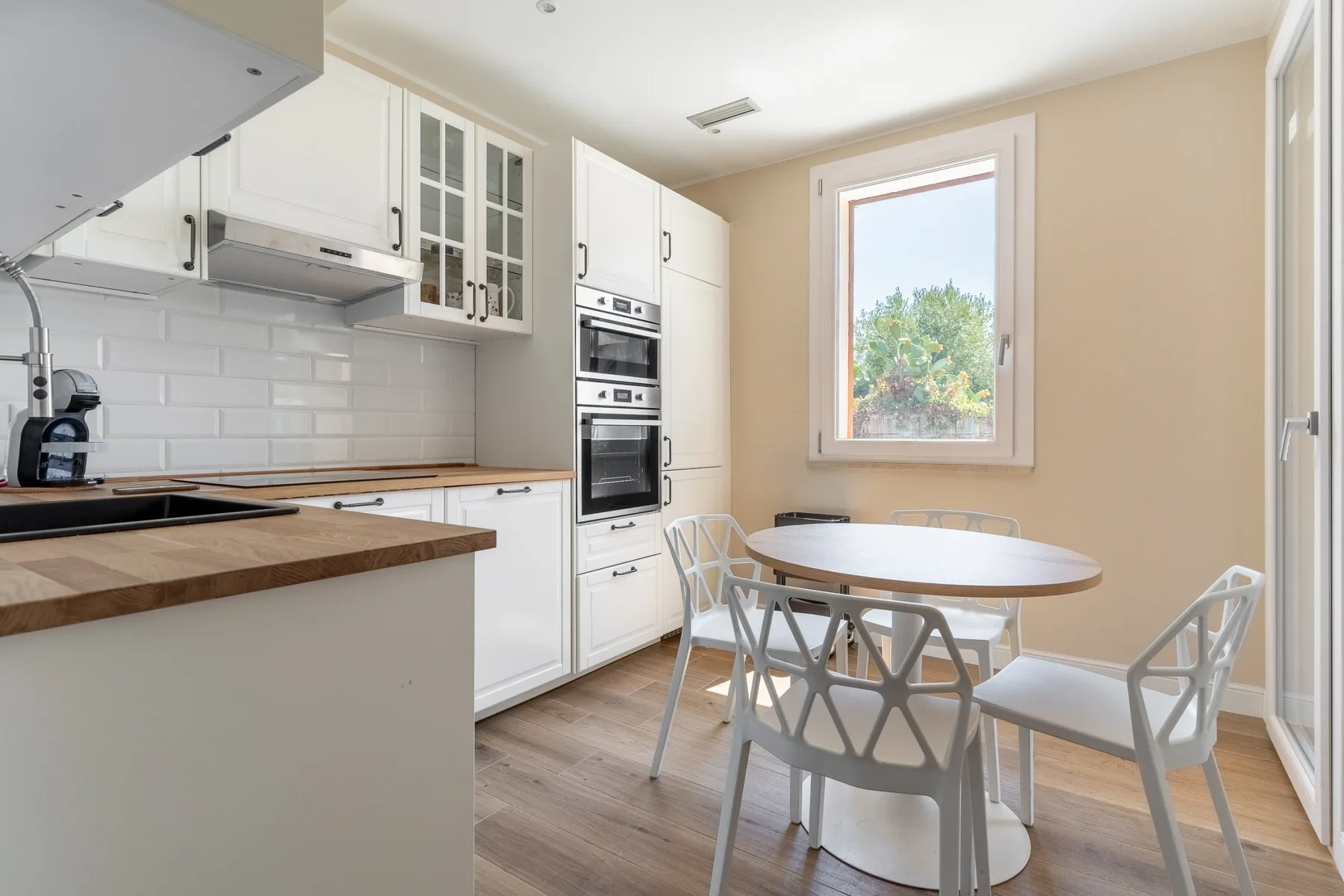 A bright kitchen and dining area with white cabinets and a round table.