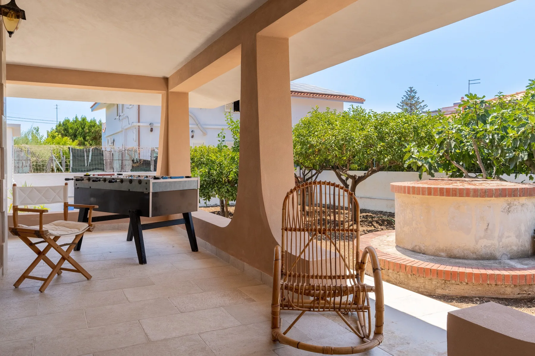 A covered patio with a foosball table, wooden seating, and a circular outdoor basin.