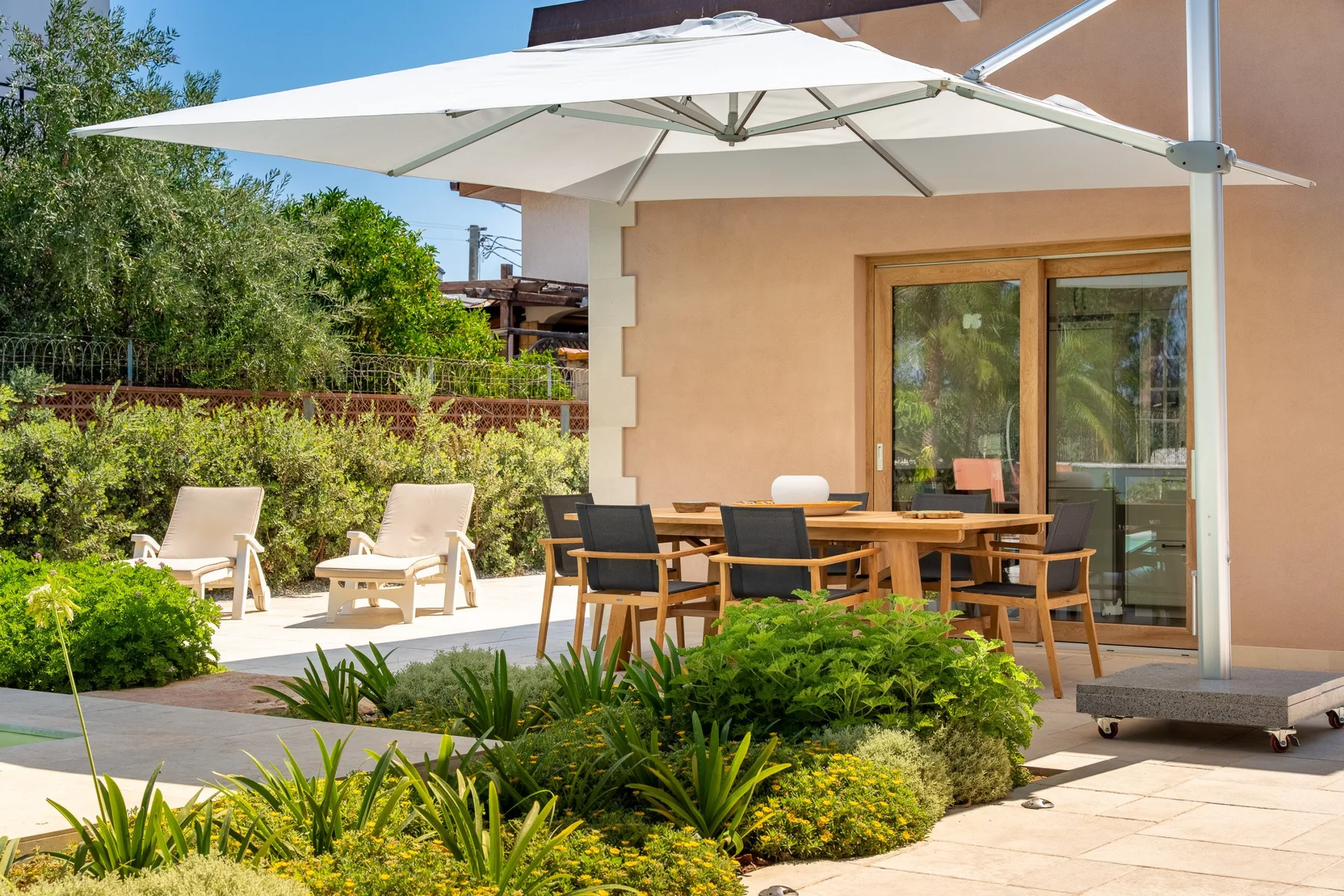 A patio dining area with a large umbrella and garden seating.