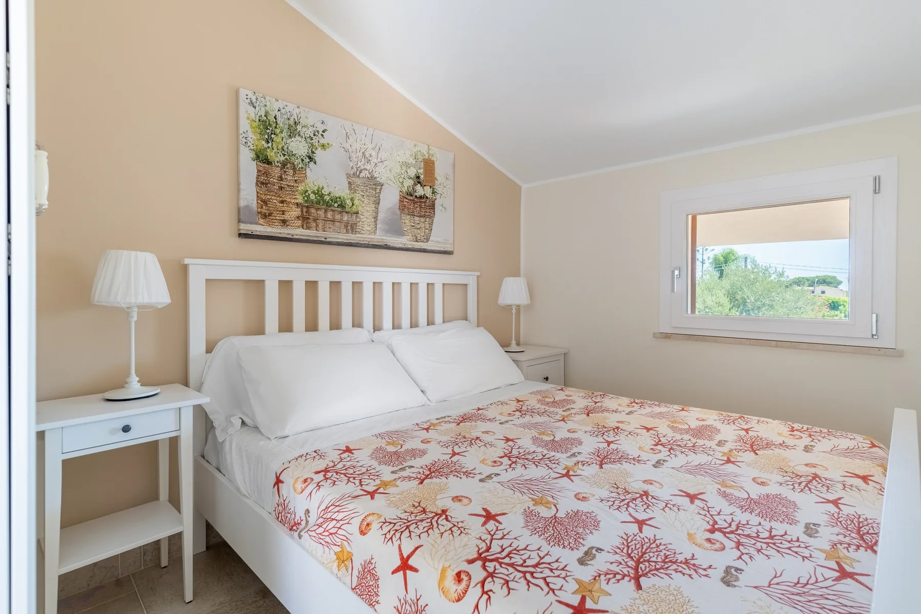 Bedroom with a bed covered in a floral-patterned spread and a window.