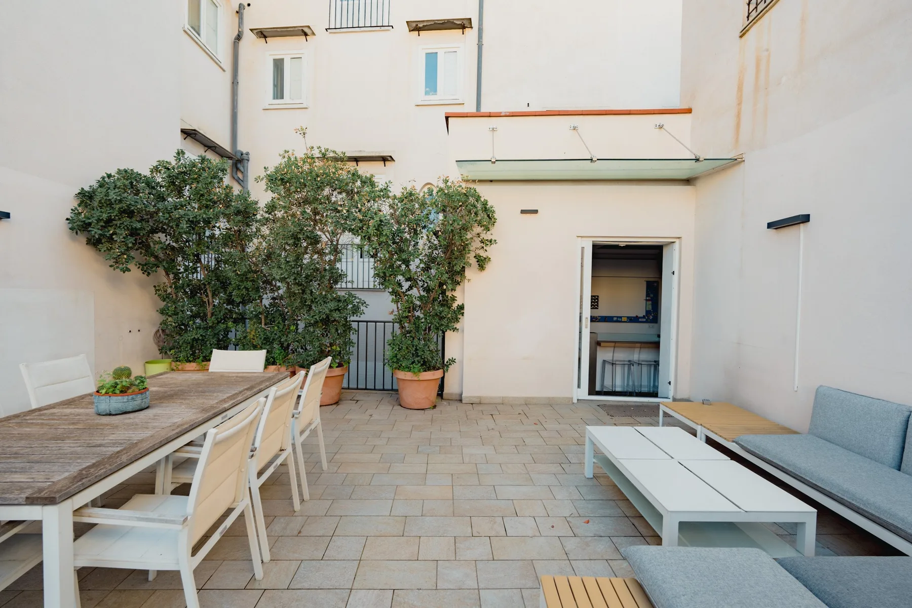A tiled courtyard patio has a dining table and outdoor seating.
