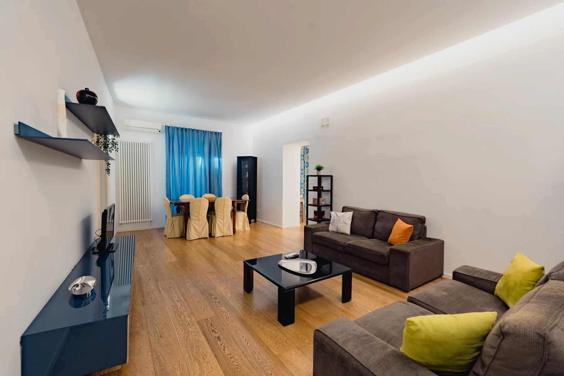 Una sala de estar con asientos, una mesa de centro y un comedor junto a la ventana.