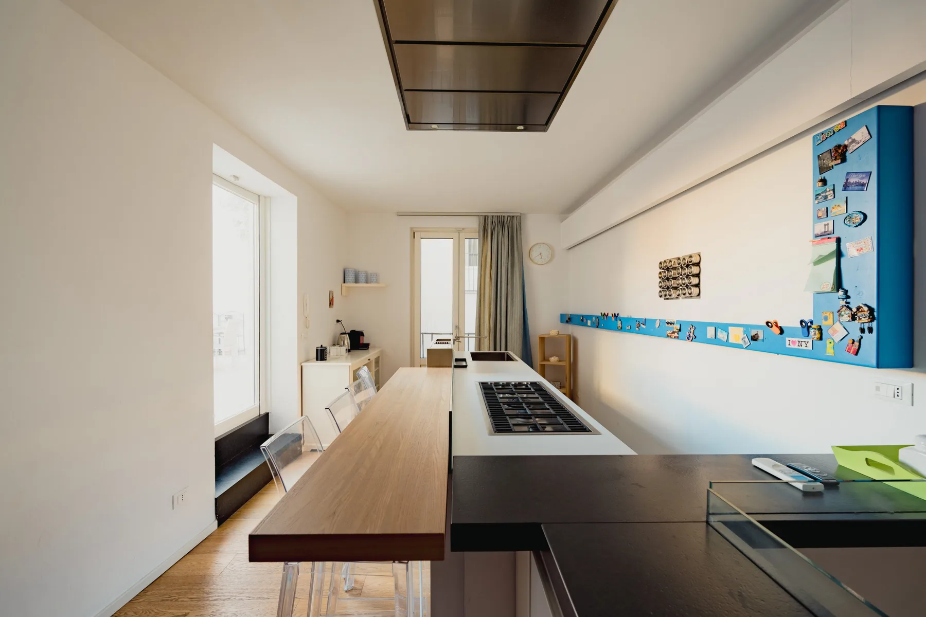 A bright kitchen with a long wooden counter and dark cooktop.