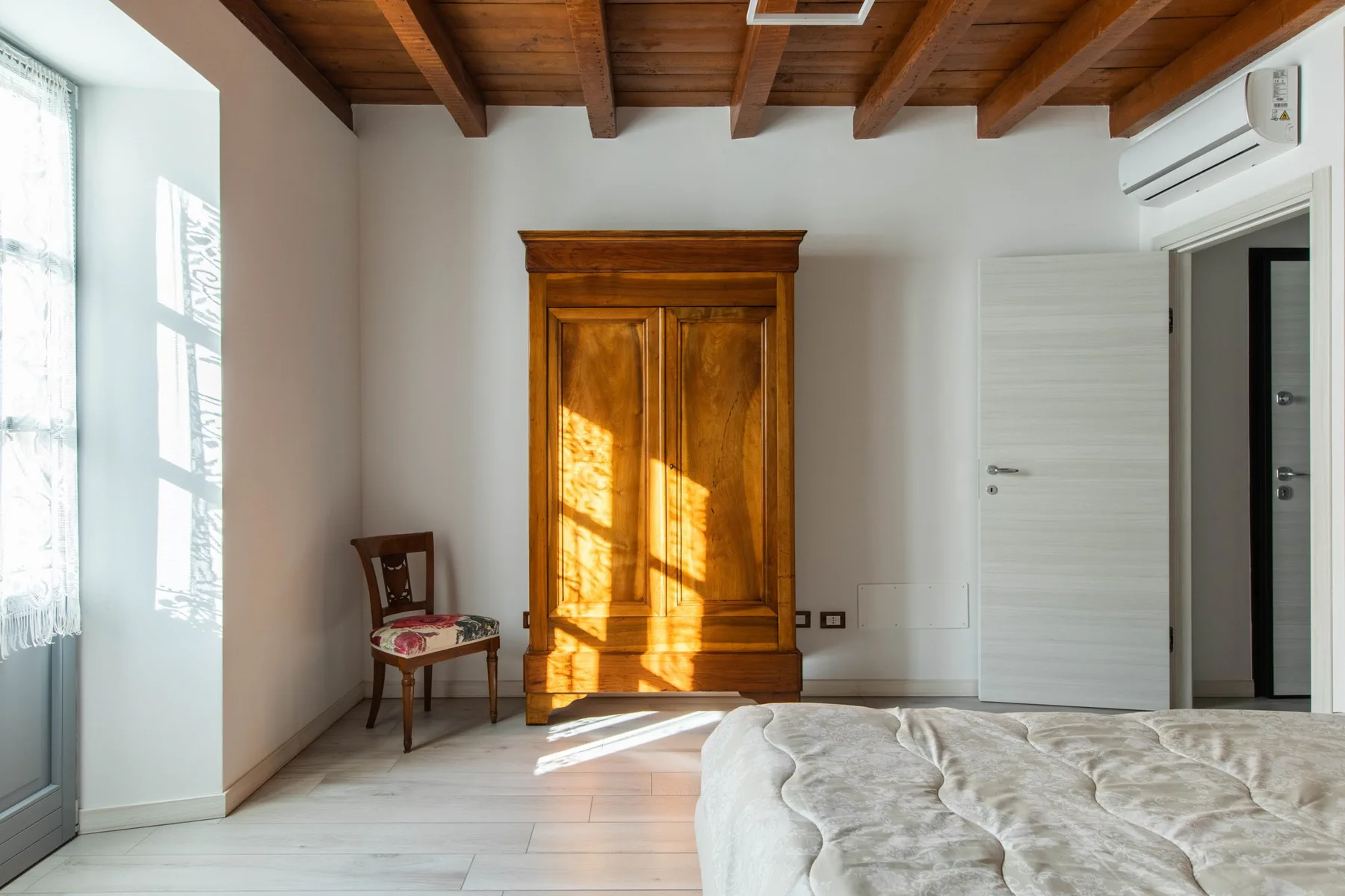 Un dormitorio luminoso con un armario de madera y una cama.