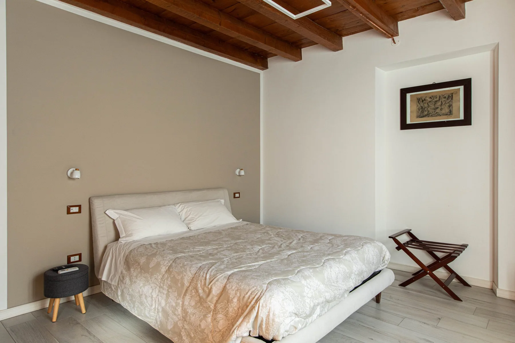 Un dormitorio con una cama doble bajo vigas de madera vistas en el techo.