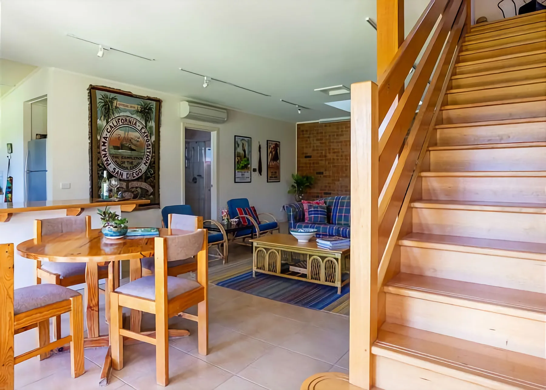 Una luminosa sala de estar y comedor con asientos, una mesa y una escalera de madera.