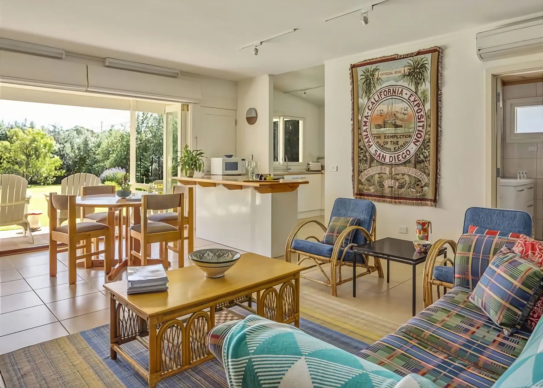 Una luminosa sala de estar y comedor se abre a un patio, con asientos y una cocina compacta.