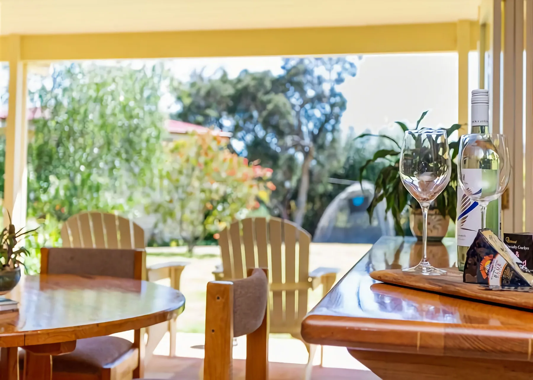 Un comedor soleado da a un jardín y tiene mesas y sillas de madera.