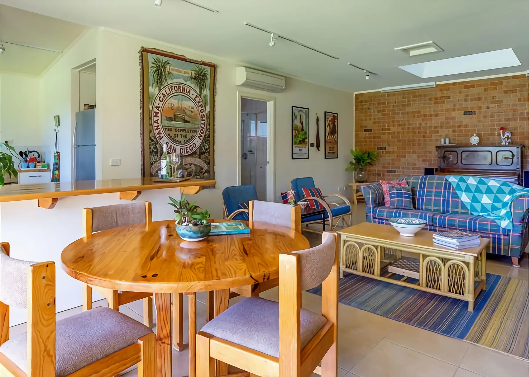 Espacio abierto de comedor y sala de estar con una mesa de madera y asientos coloridos.