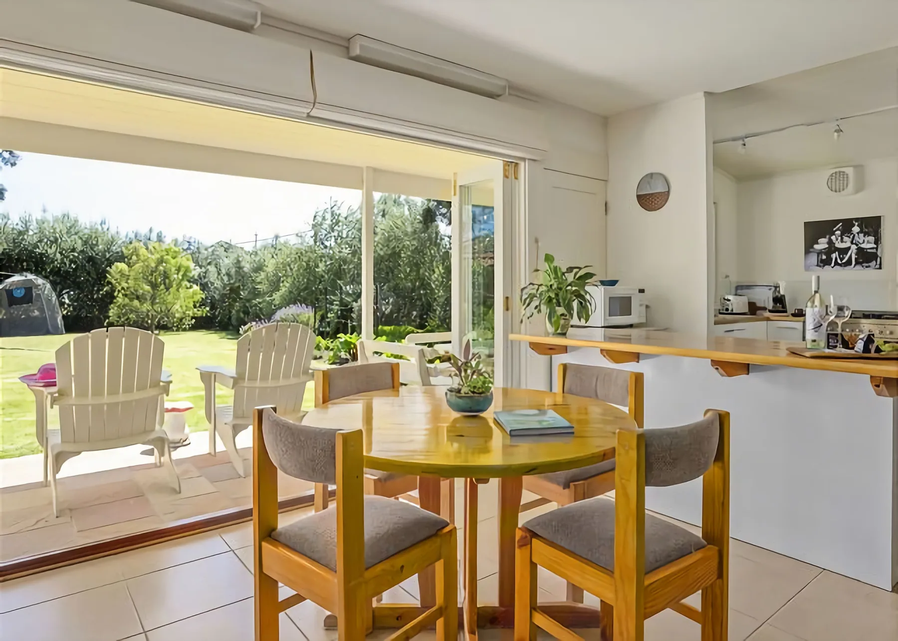 Un comedor se abre a un patio, con una encimera de cocina al fondo.