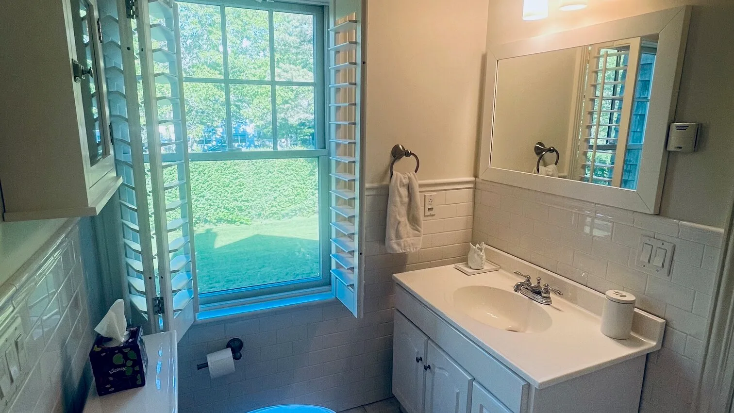 Un baño con lavabo y una ventana grande con vista a la vegetación.