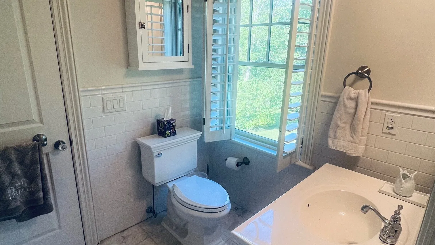 Un baño con inodoro, bañera y una ventana con vista a la vegetación.