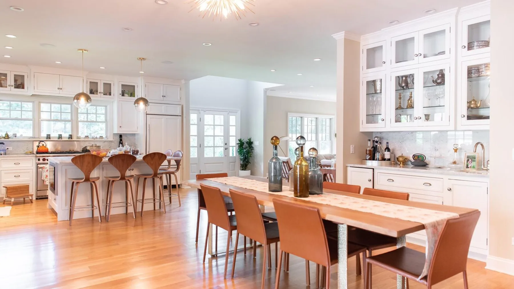 Una luminosa cocina y comedor con una mesa larga de madera y asientos junto a la barra.