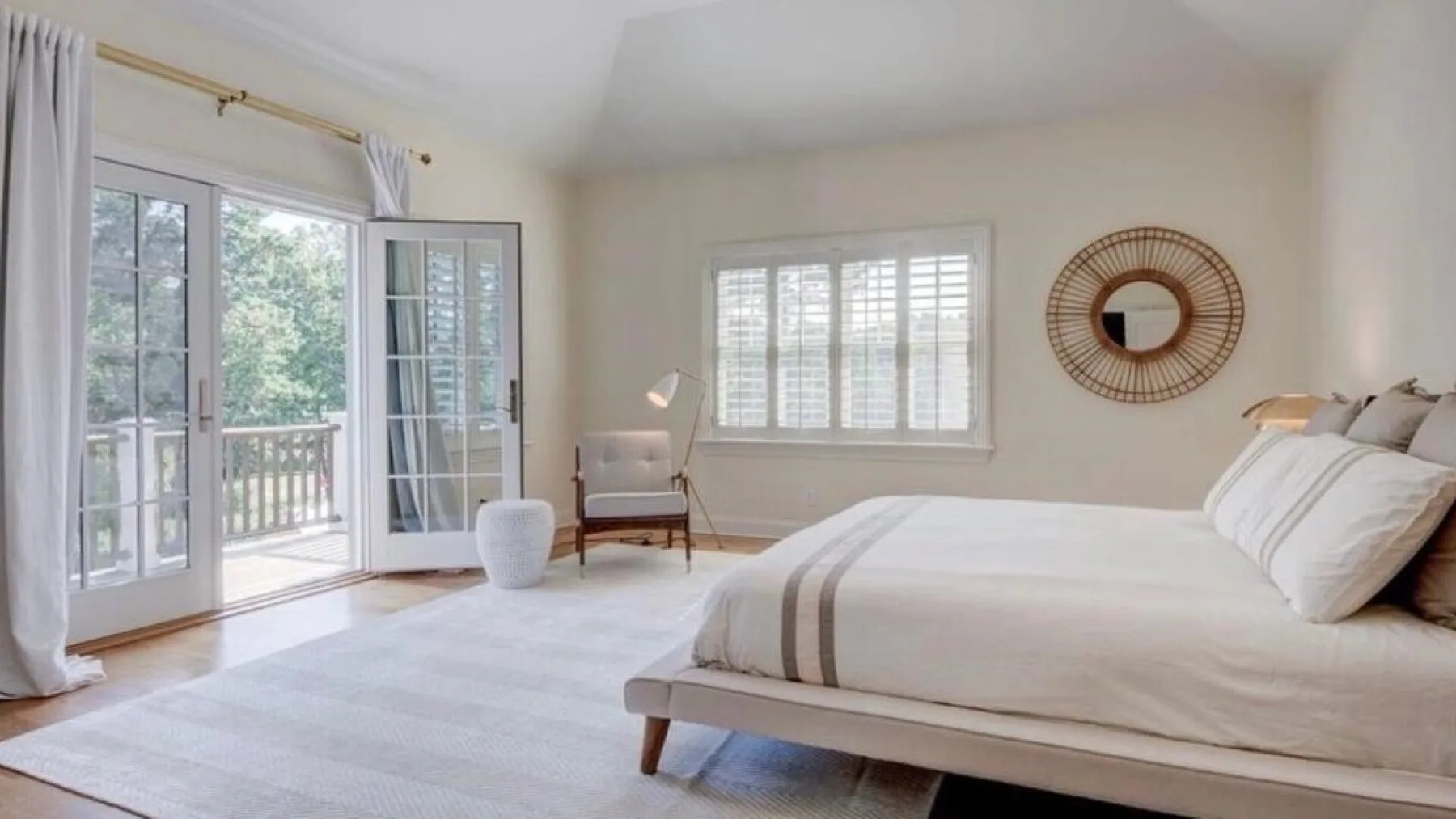 Un dormitorio luminoso con una cama grande y ventanas que dan a un balcón.