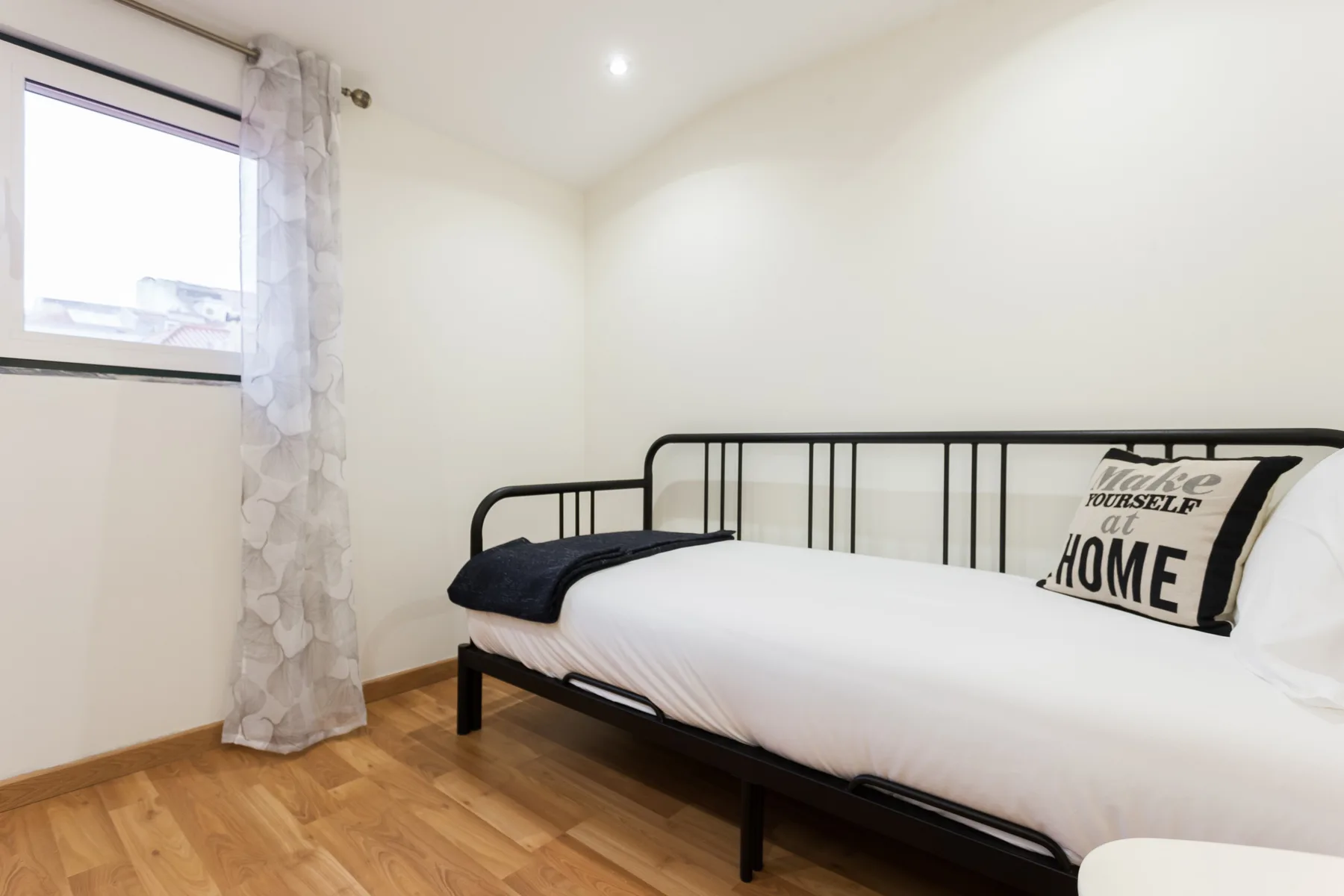 Dormitorio con una cama de metal negro junto a una ventana.