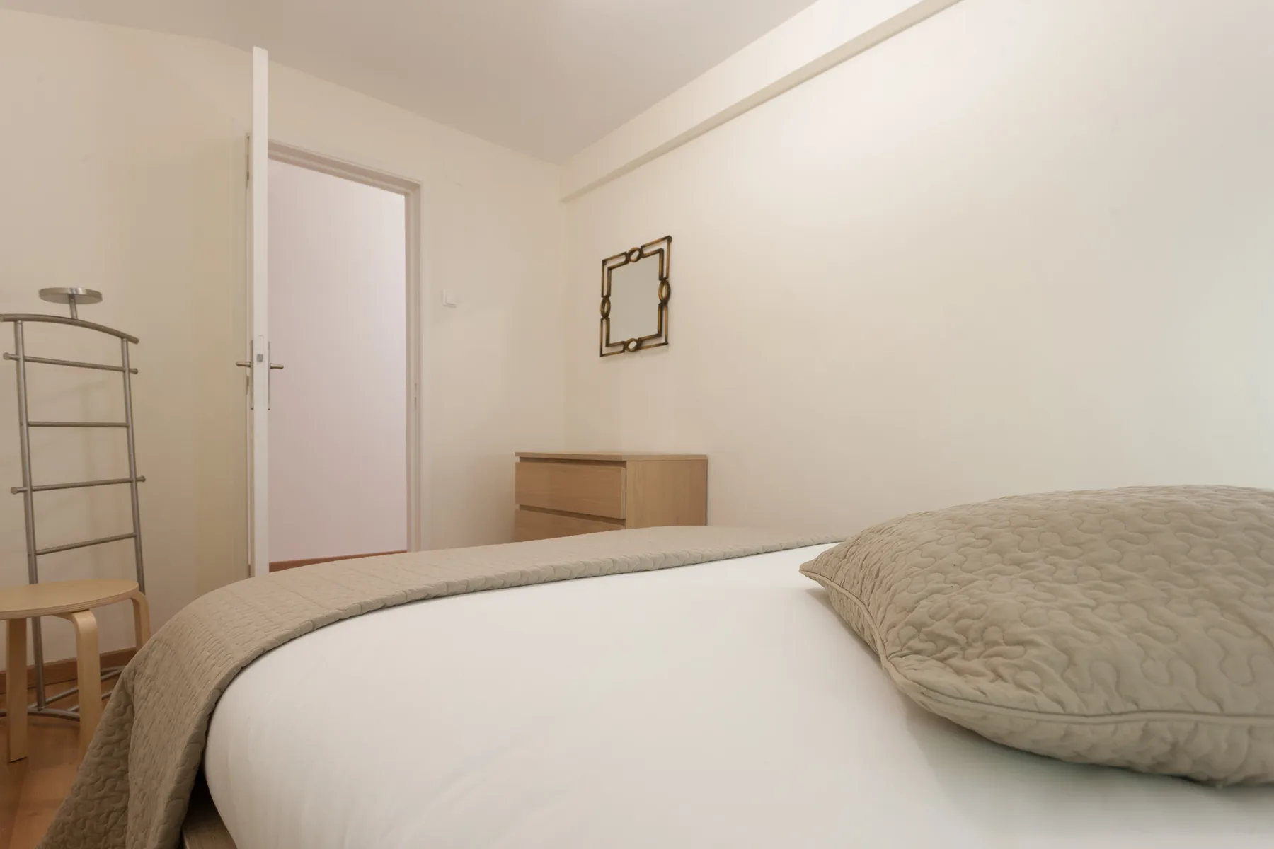 Un dormitorio con una cama y una cómoda pequeña de madera.