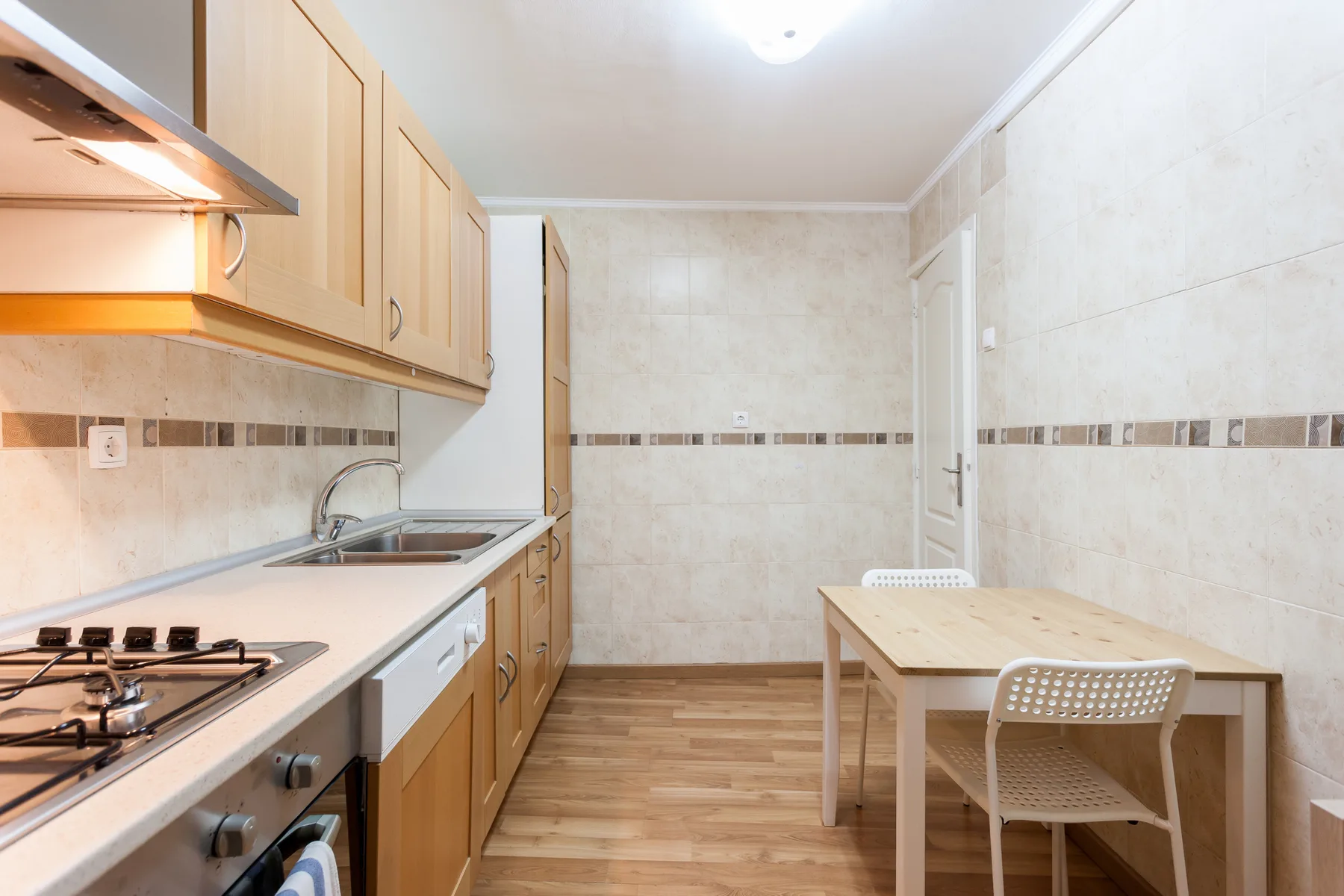 Una cocina compacta con zona de comedor, armarios de madera y una mesa.