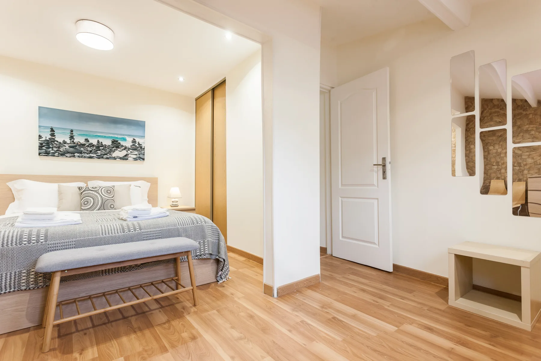 Un dormitorio con una cama, una lámpara de noche y suelo de madera.